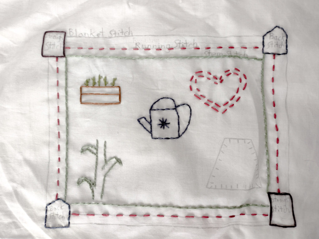 embroidery sampler pink running stitch heart, blue watering can back  stitch, green corn stalk stem stitch, brown flower box straight stitch, plus borders