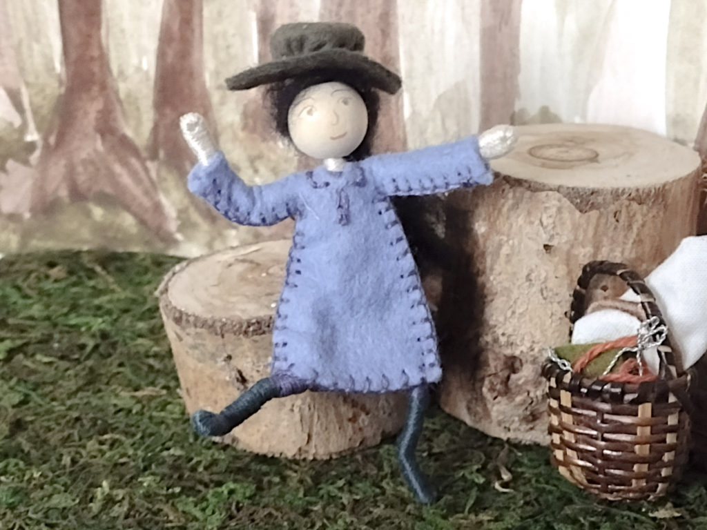 A tiny wood nymph doll dancing. Behind her are stumps and to the side of her is her tiny embroidery basket