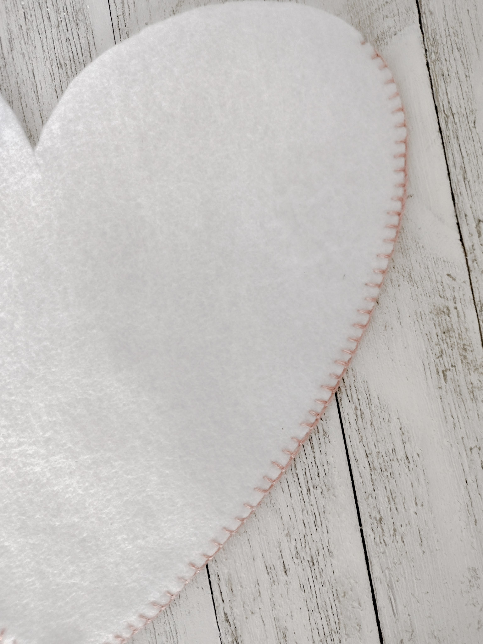 Side of white flet heart with pink floss blanket stitch