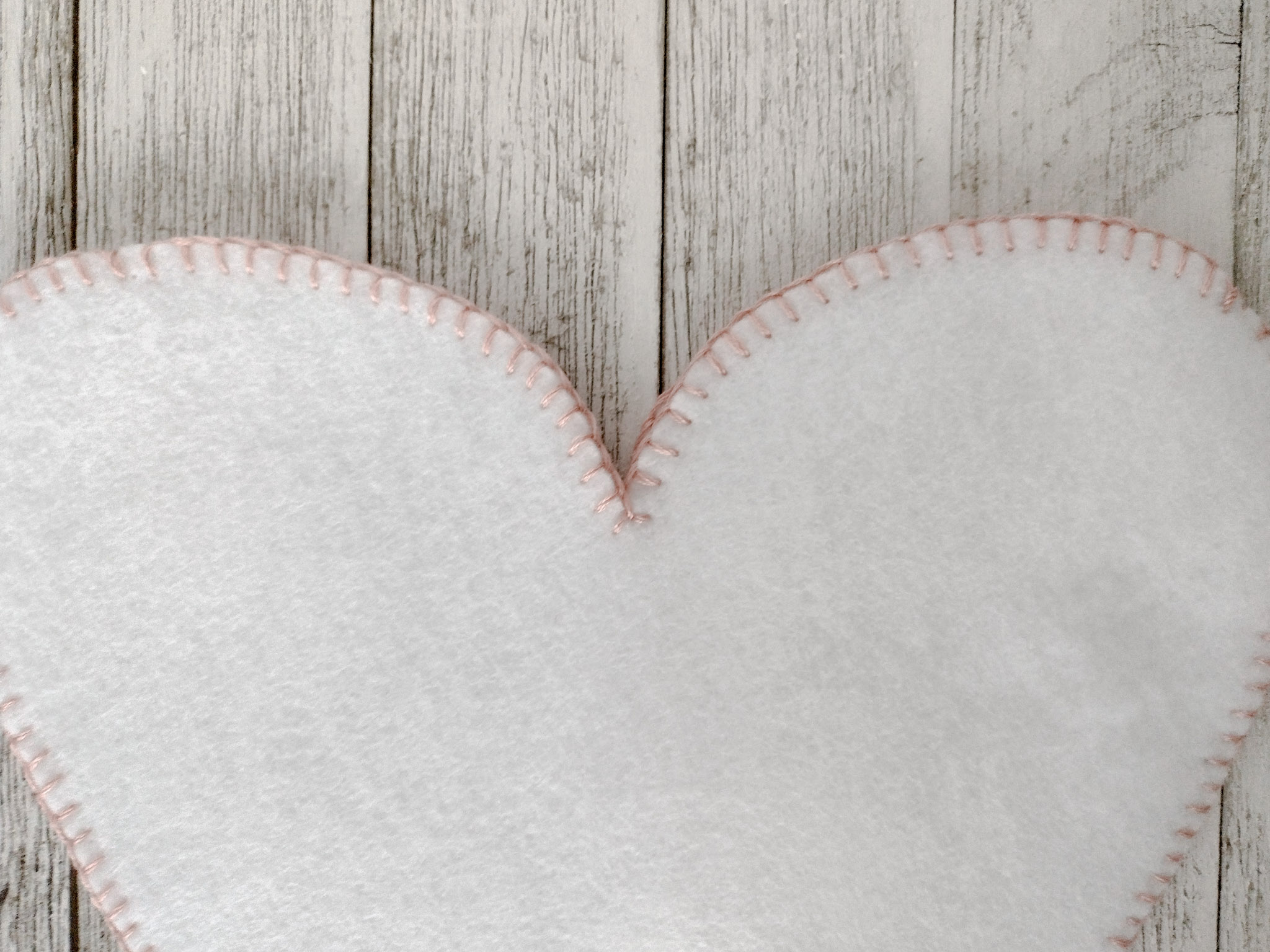 close up top of white felt with pink blanket stitch 