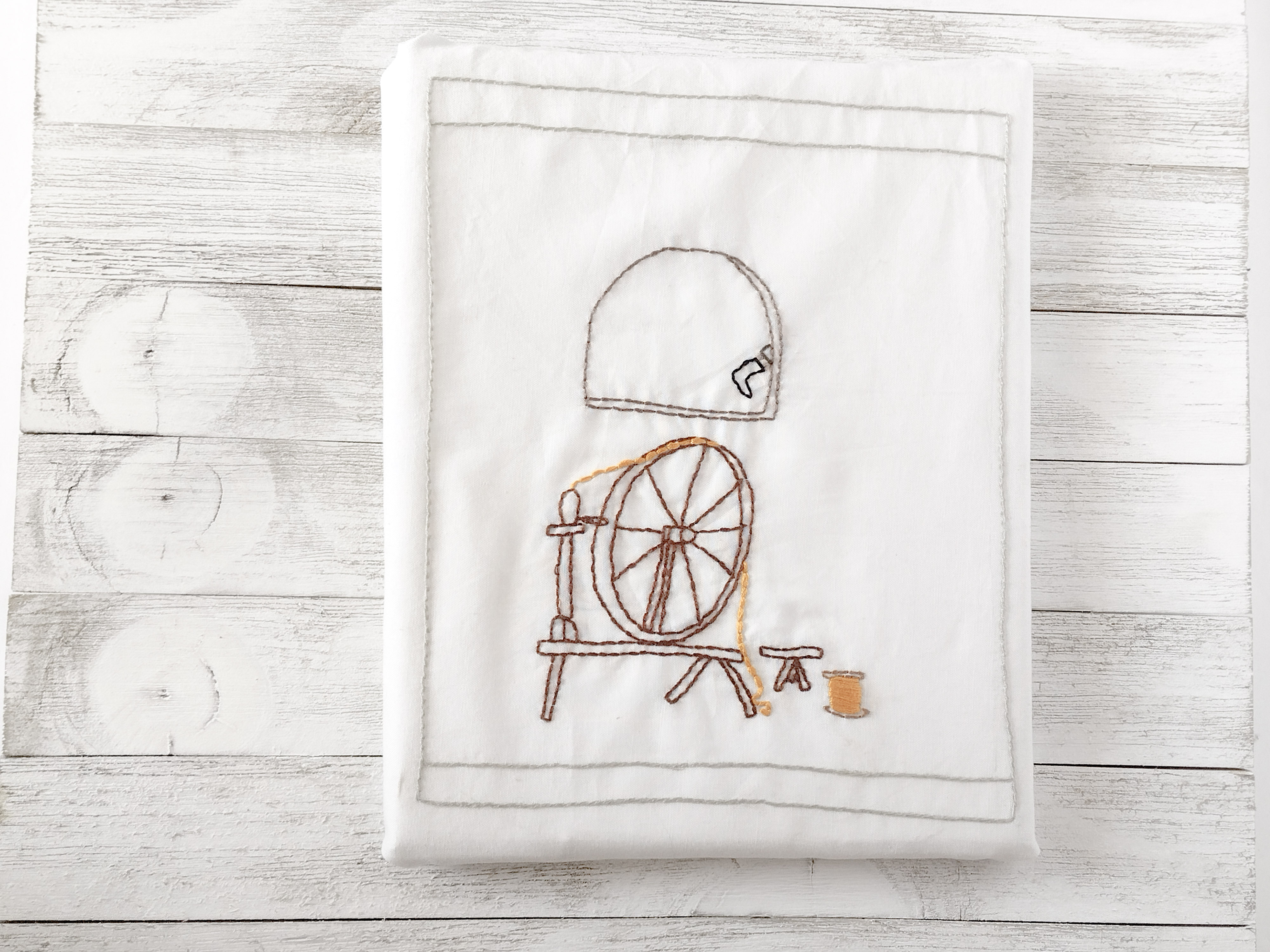 embroidery pattern of a spinning wheel, gold thread, and a window