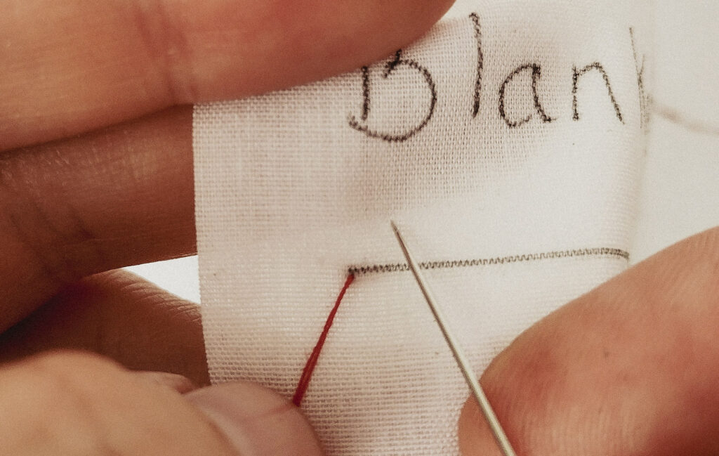 Needle going into white fabric to form a blanket stitch