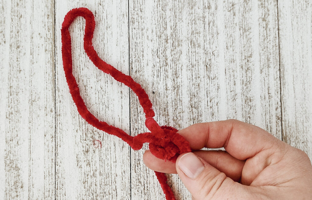 Close up of first finger knitting stitch in red Christmas colored yarn