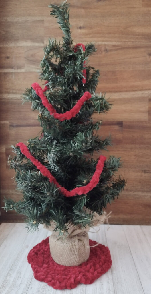 Mini Christmas tree with red finger knitted garland, and red finger knitted mini circle rug.